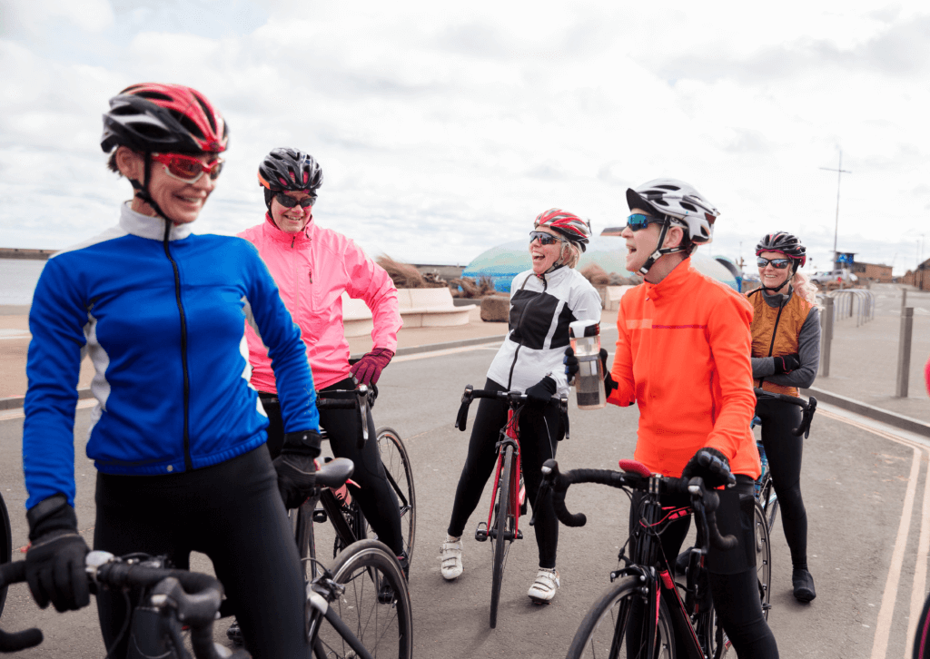a cycling group standing on their bikes, chatting and laughing