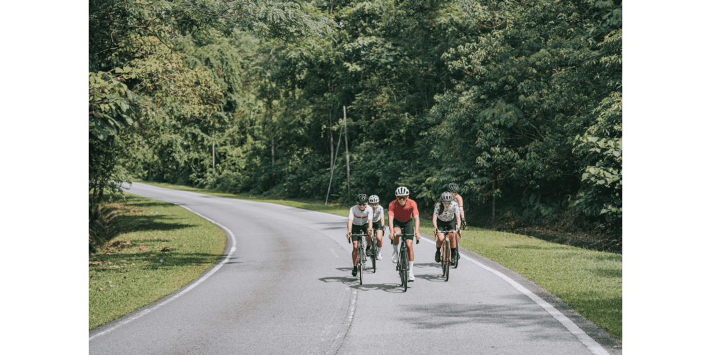a group of cyclist cycling along the road with trees behind them