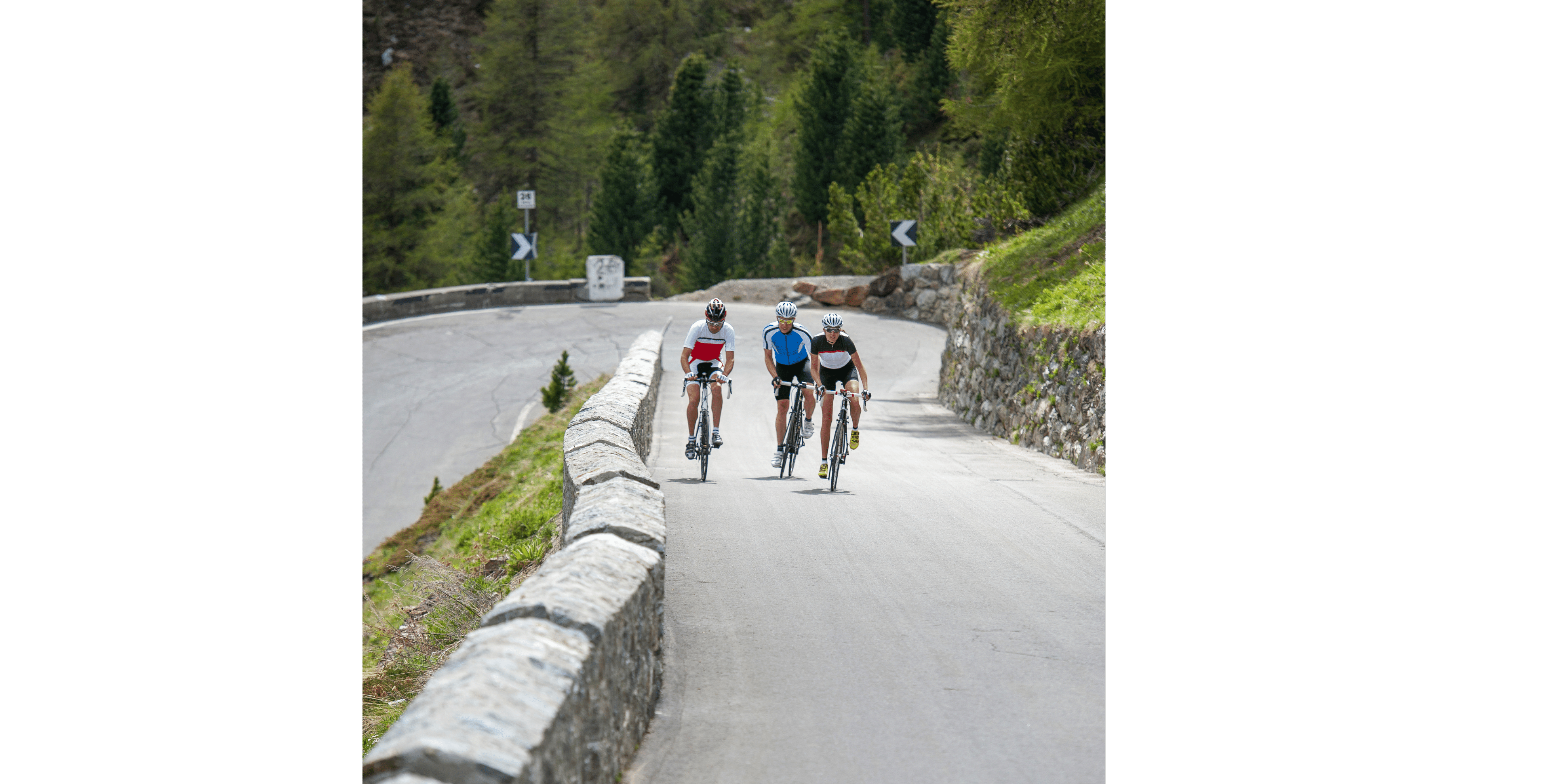 three cyclists cycling up a hill together