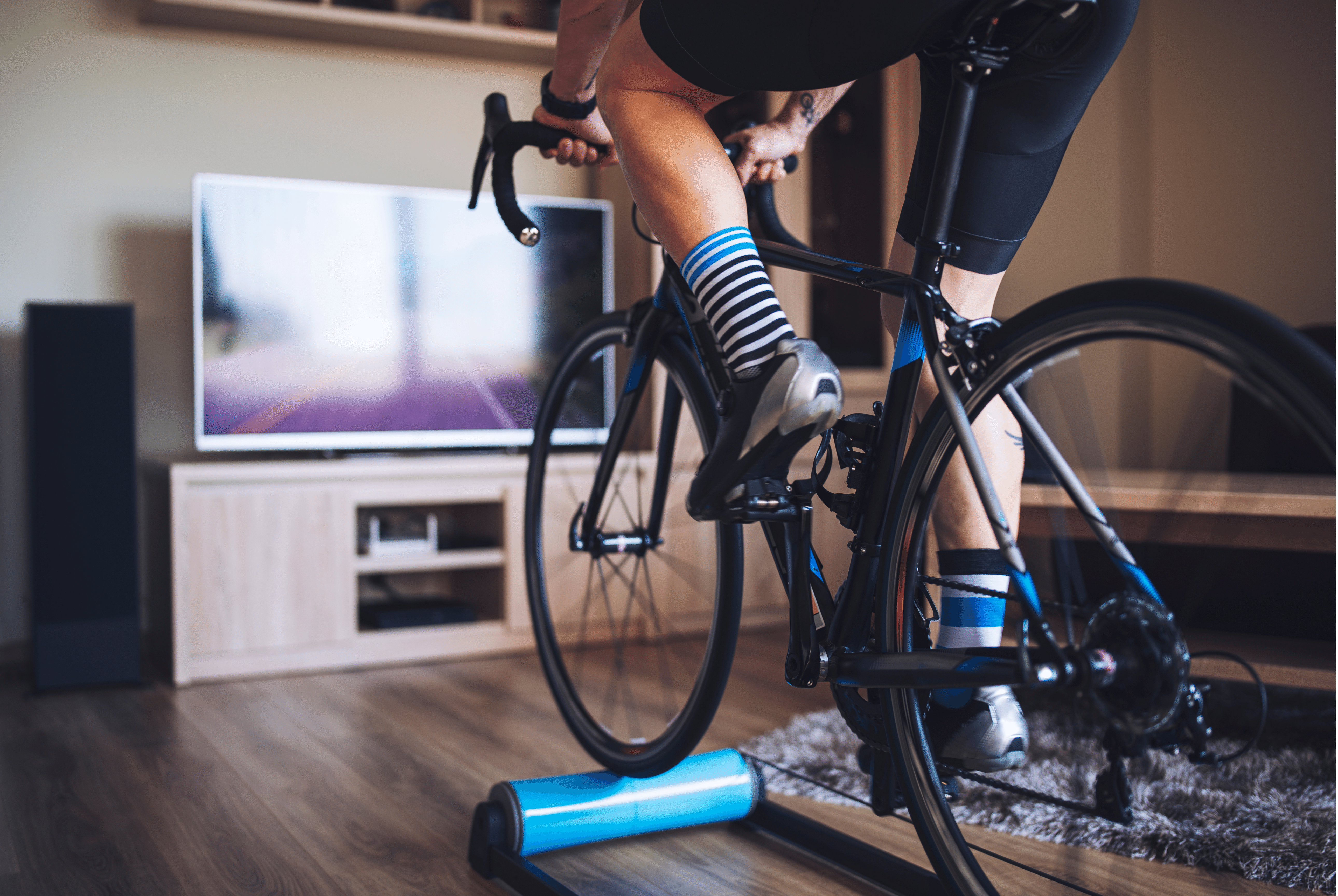 a cyclist using an indoor bike trainer, in front of the tv in a living room