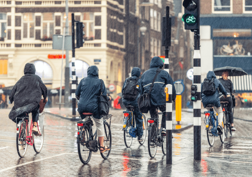 a bunch of people cycling in the rain on a city road
