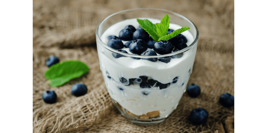 a glass cup with greek yogurt, with blueberries on top