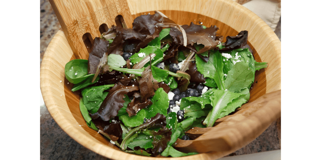 a salad bowl with a mixture of dark leafy green vegetables 