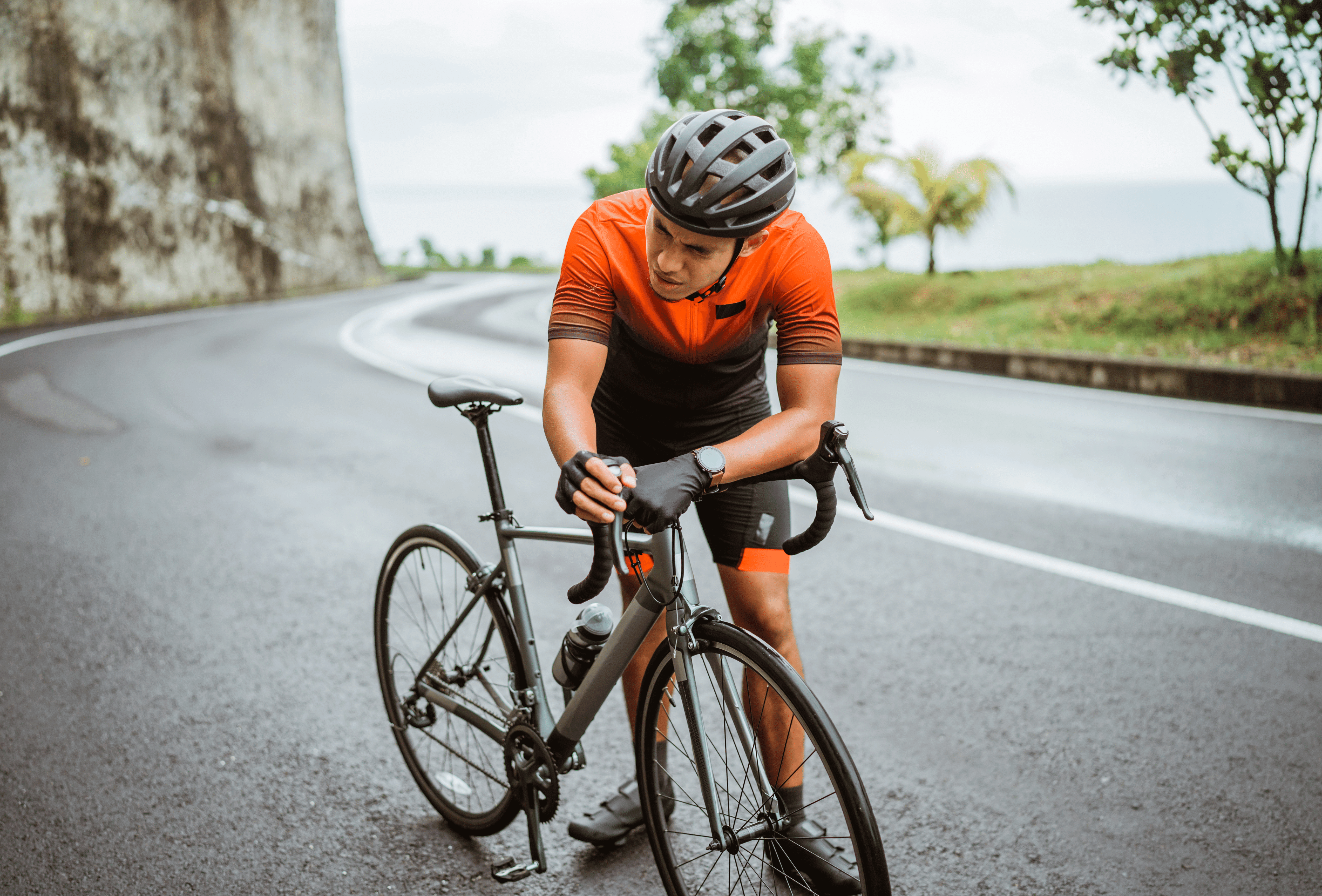 a male cyclist bent over his bike in fatigue