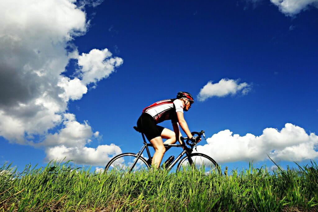 a man cycling a road bike alongside grass 