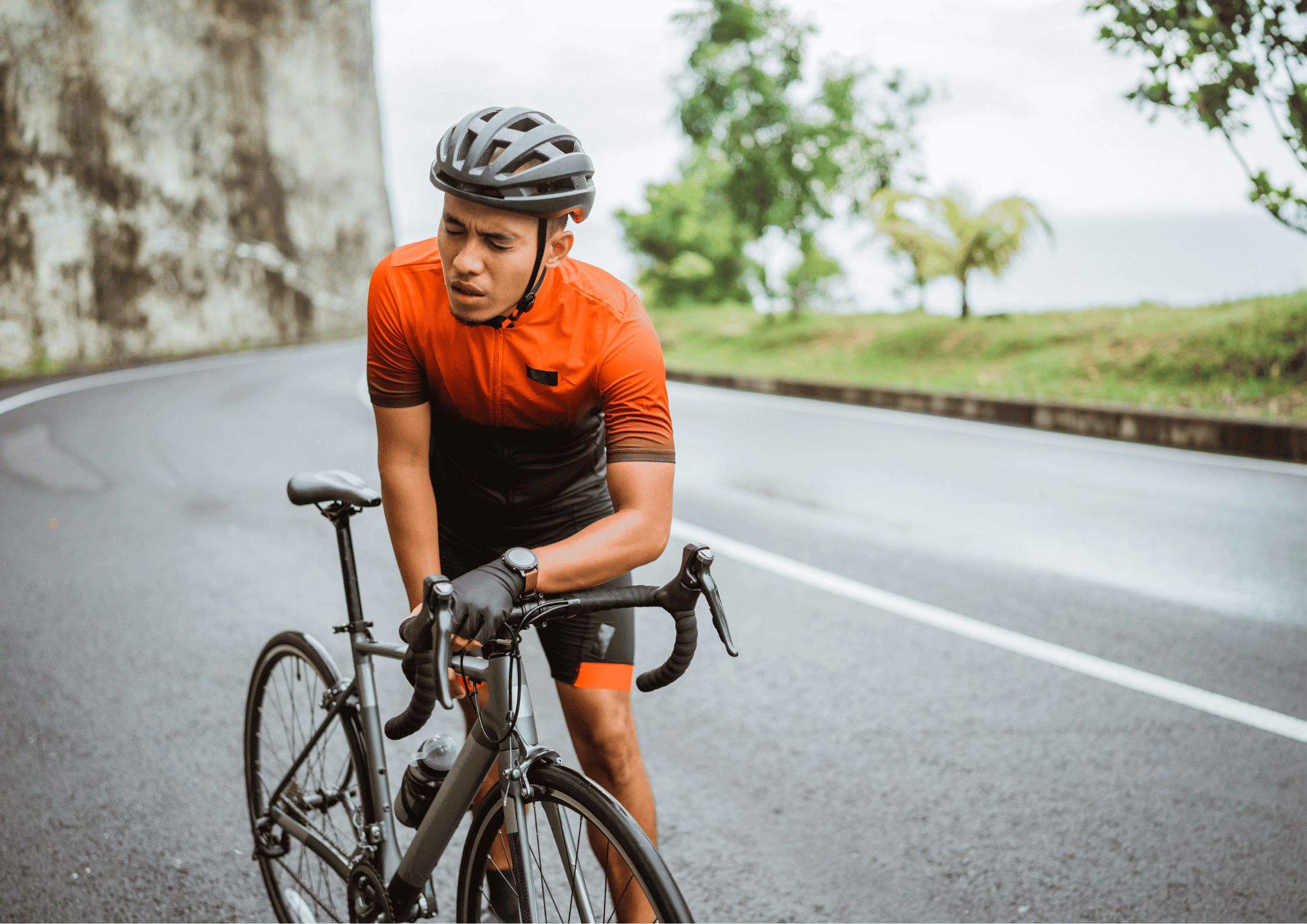 a male cyclist bent over his bike in fatigue