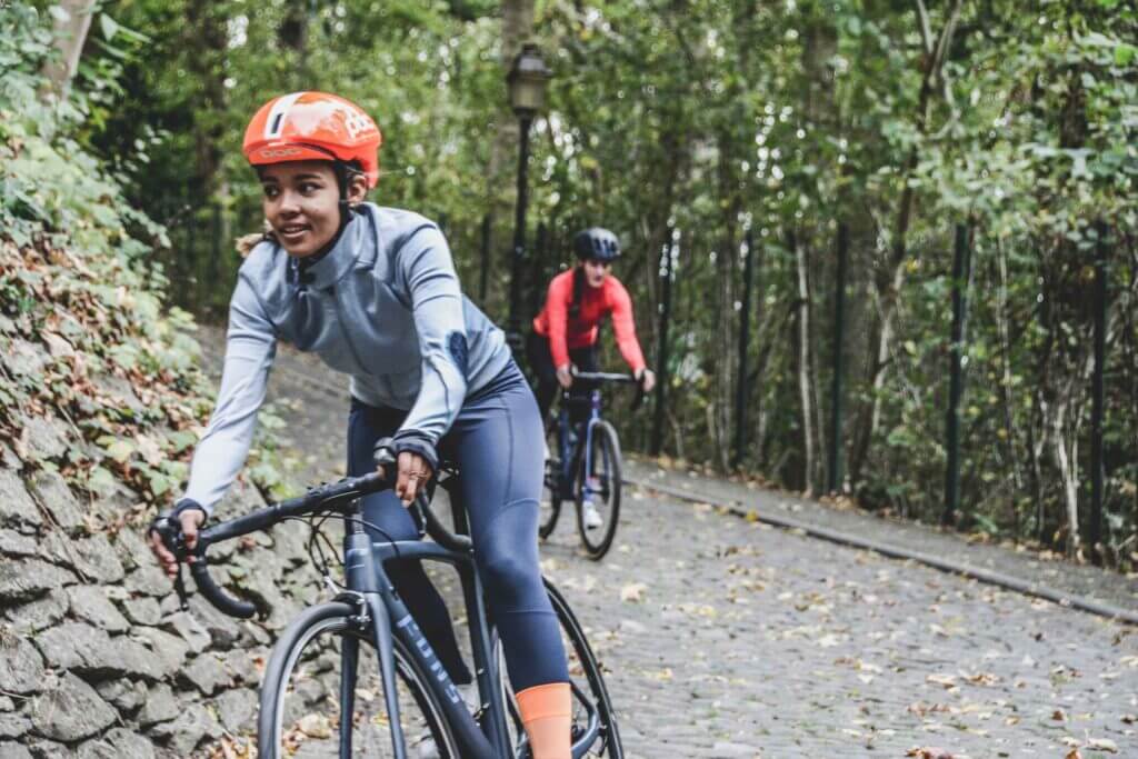 a woman smiling as she cycles around a bend in a forest
