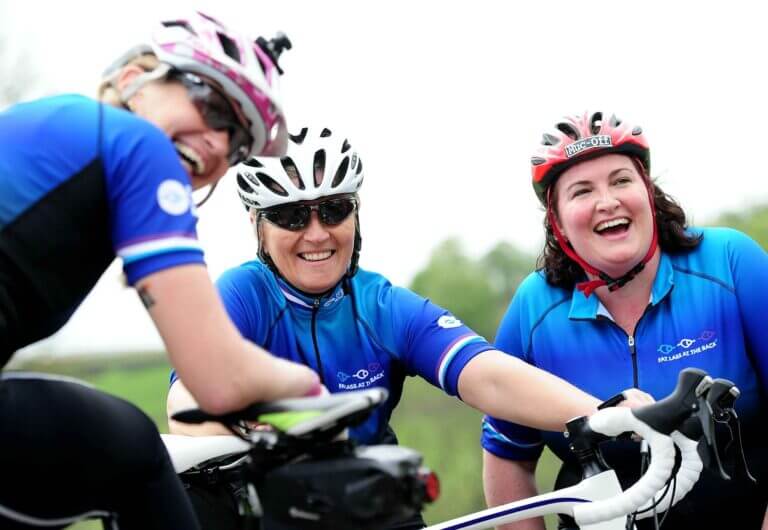 three female cyclists laughing and smiling