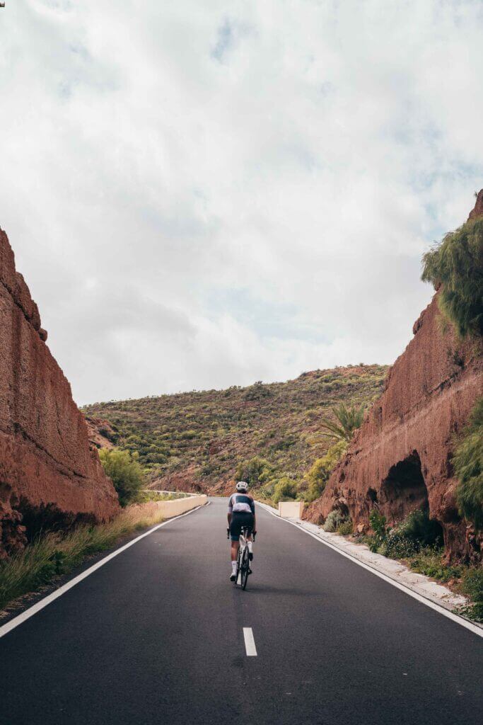 a cyclist cycling up a hill surrounded by mountains