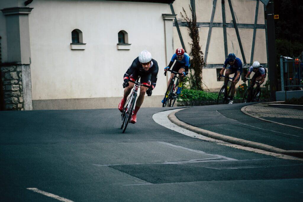a line of 3 cyclists racing around a bend