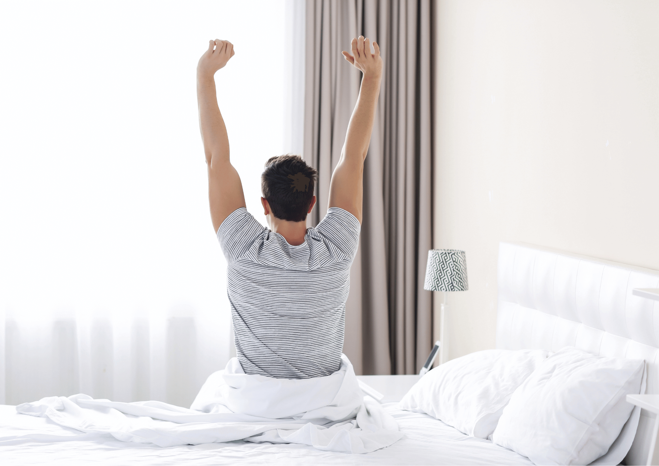 a man sitting on the bed stretching his arms up after a sleep