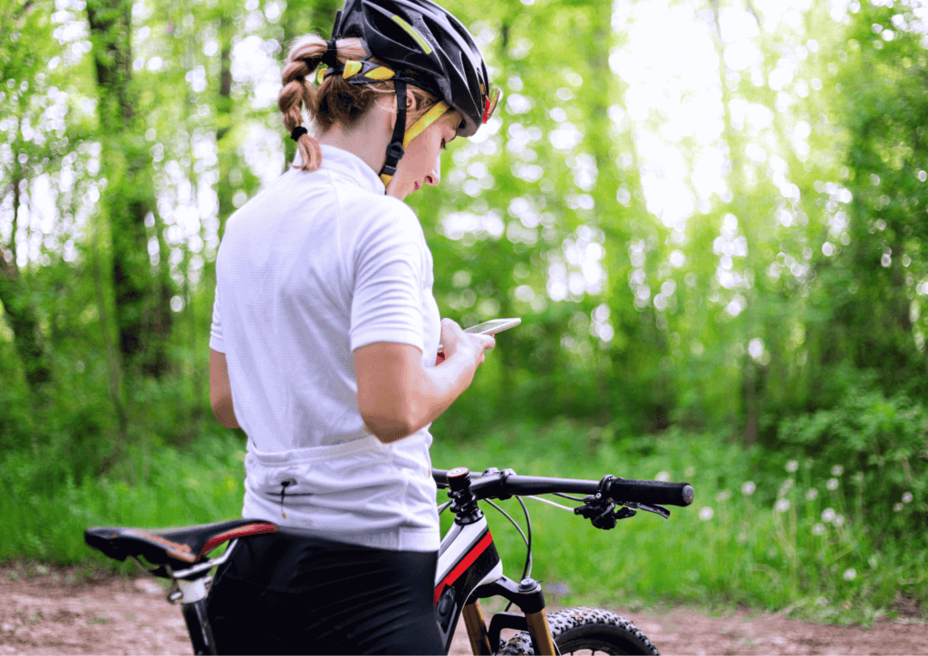a female cyclist stopped, looking at her phone