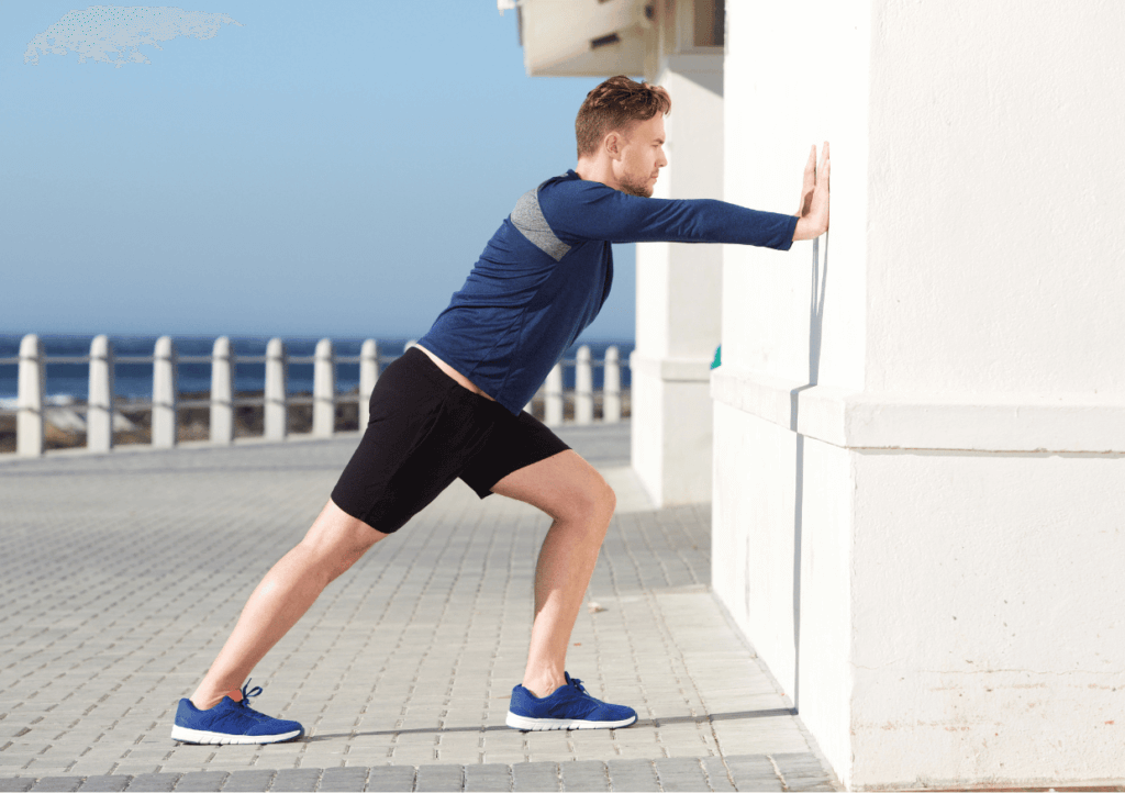 a man outside stretching his calves against a wall