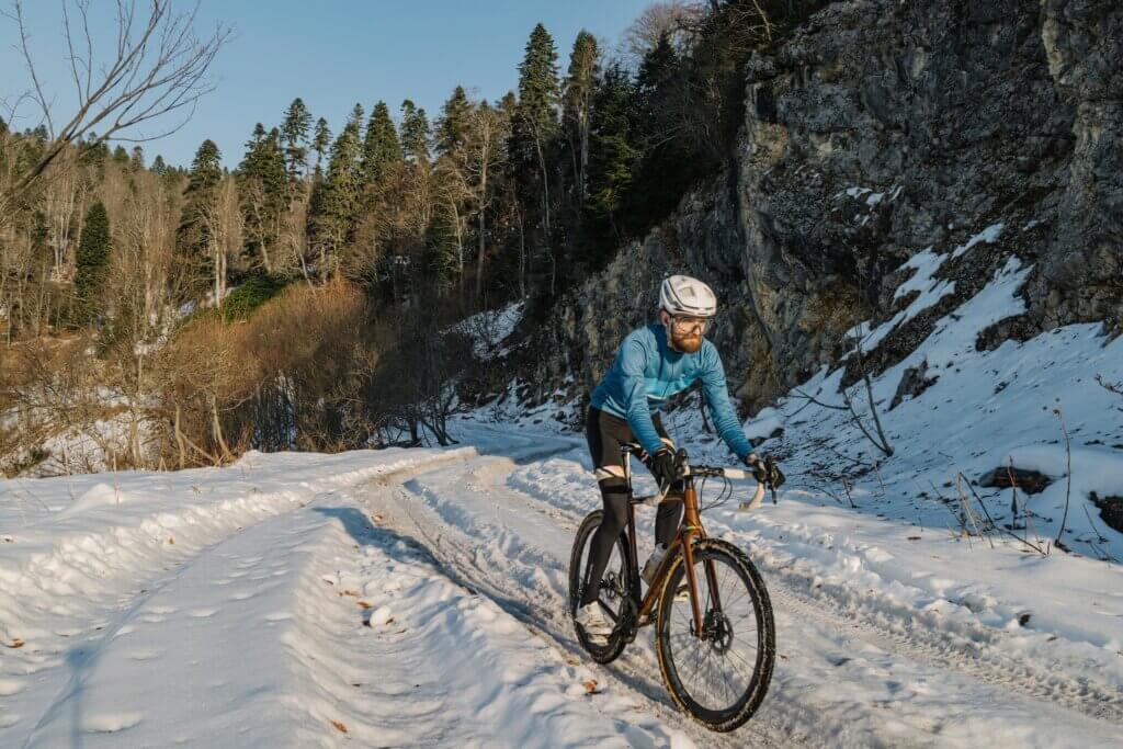 a man riding a gravel bike down a snow covered road