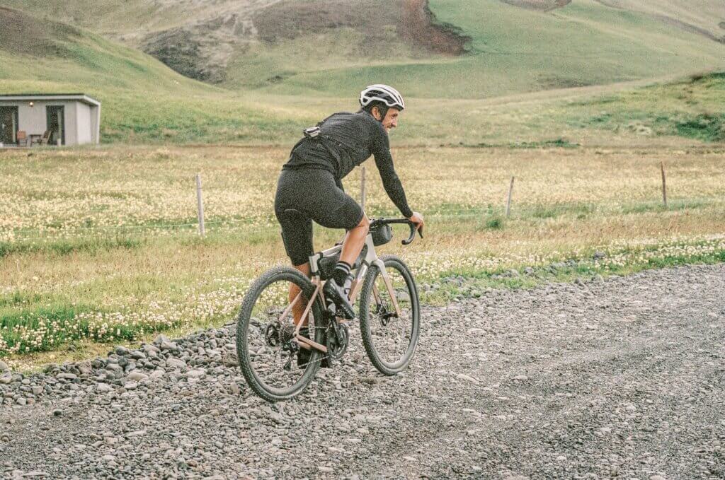 a male cyclist riding a gravel bike on a gravel road