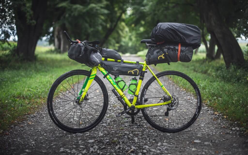 a green gravel bike equipped with bags for Bikepacking