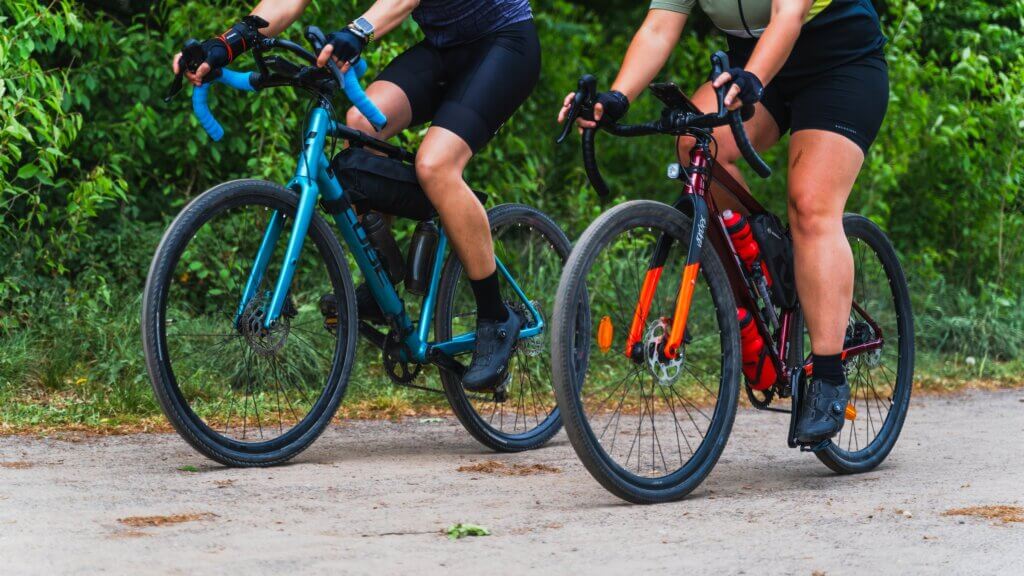 a couple of people riding gravel bikes down a road