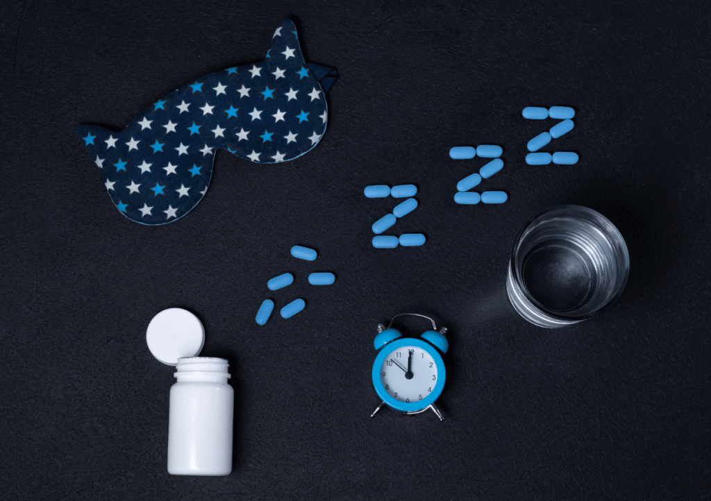 a collection of sleeping pills, alarm clock, and eye mask