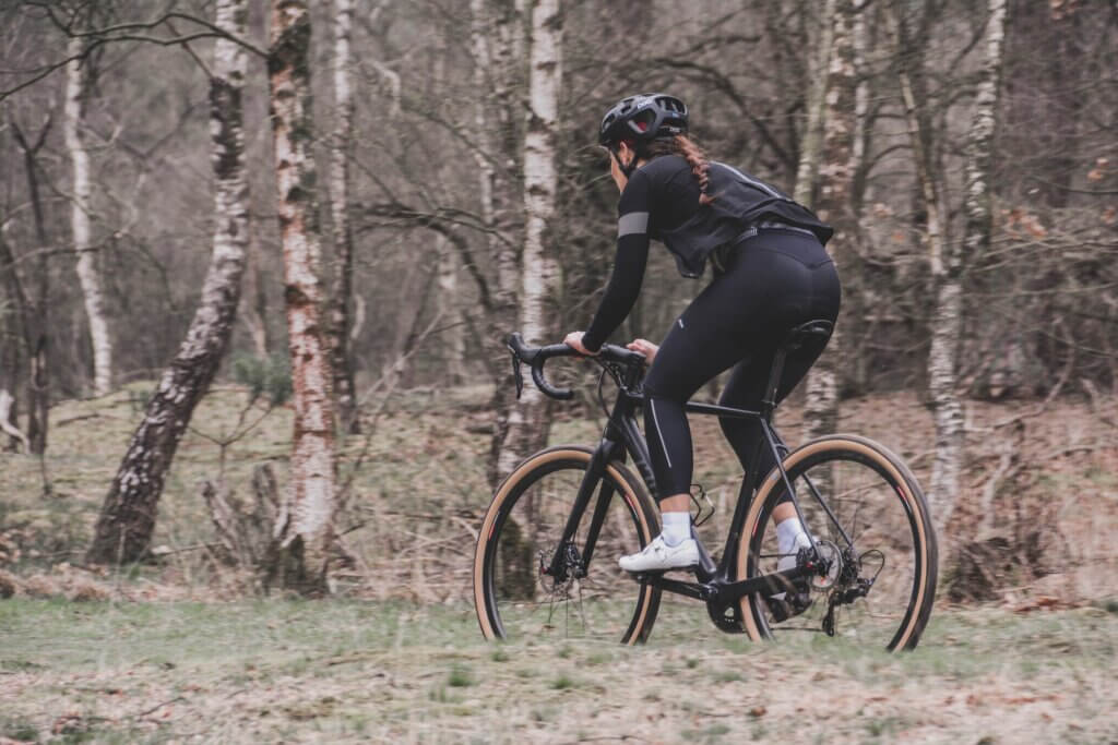 a woman cycling during winter through a woods