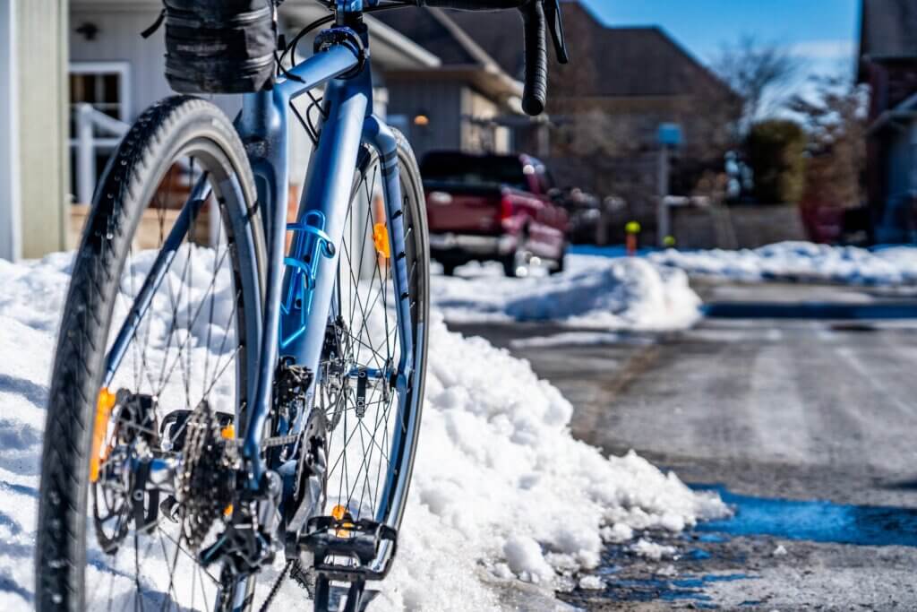 a blue gravel bike with winter tires on a snow covered road during daytime