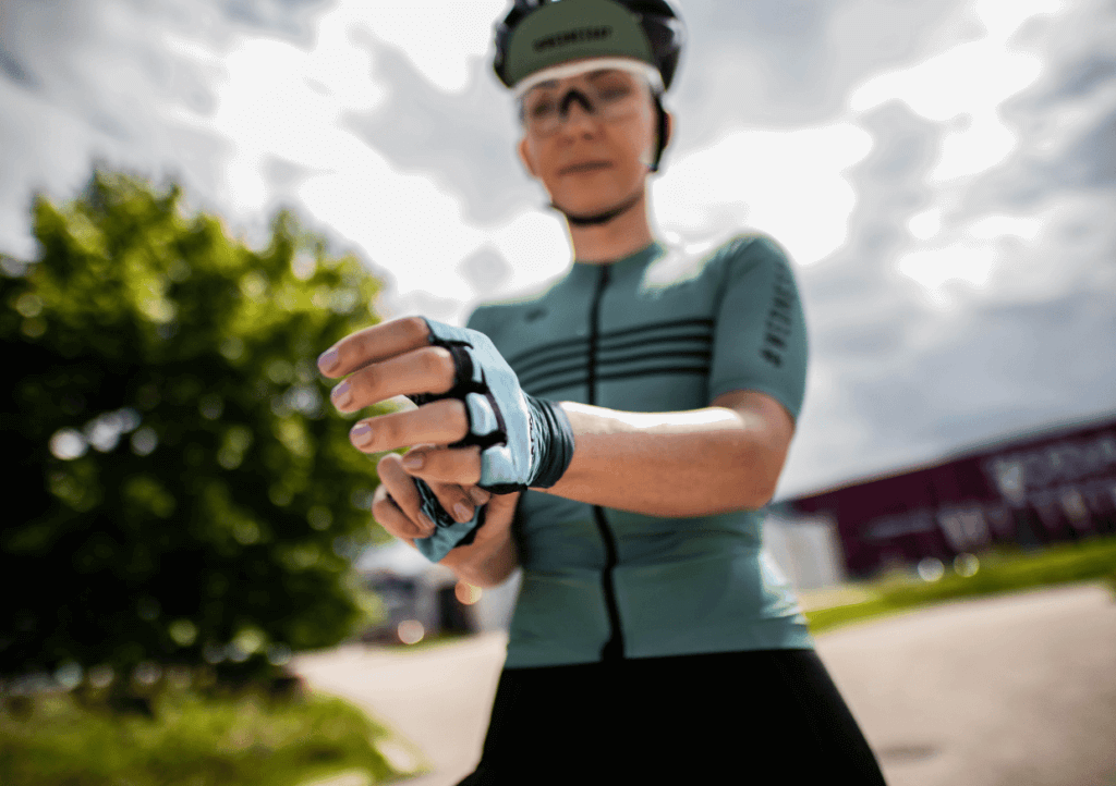 a female cycling wearing cycling gear and putting on gloves